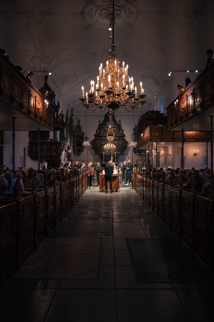 Holmens Kirke by candlelight, with a golden chandelier above the aisle and carved wooden pews