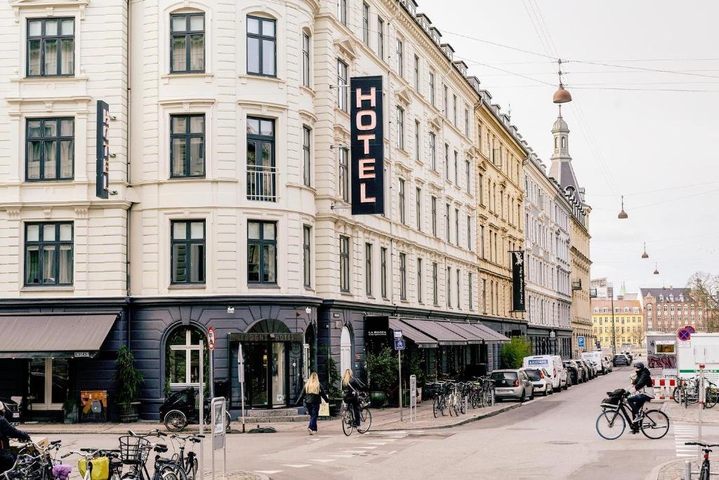 The cream-coloured corner building of Ibsens Hotel on a quiet Copenhagen street with bicycles outside