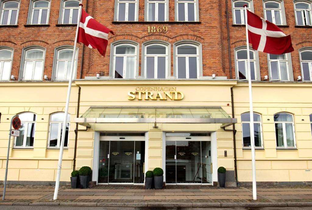 The entrance of Copenhagen Strand with Danish flags outside the 1869 brick building on Havnegade