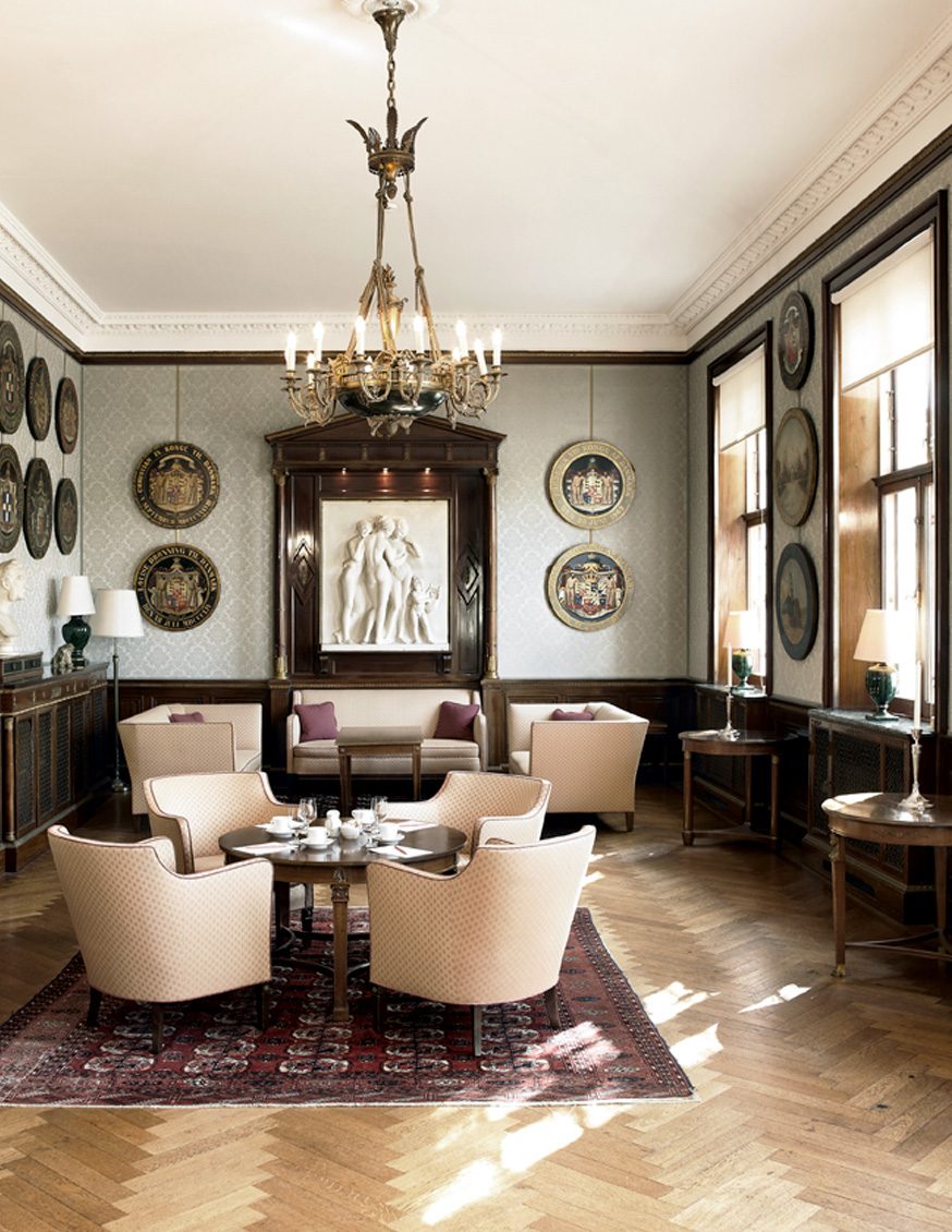 A salon at Sølyst with a chandelier, herringbone floor and soft armchairs